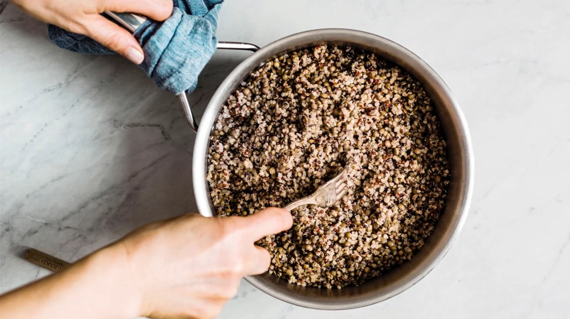 stirring cooked quinoa in a pot with fork